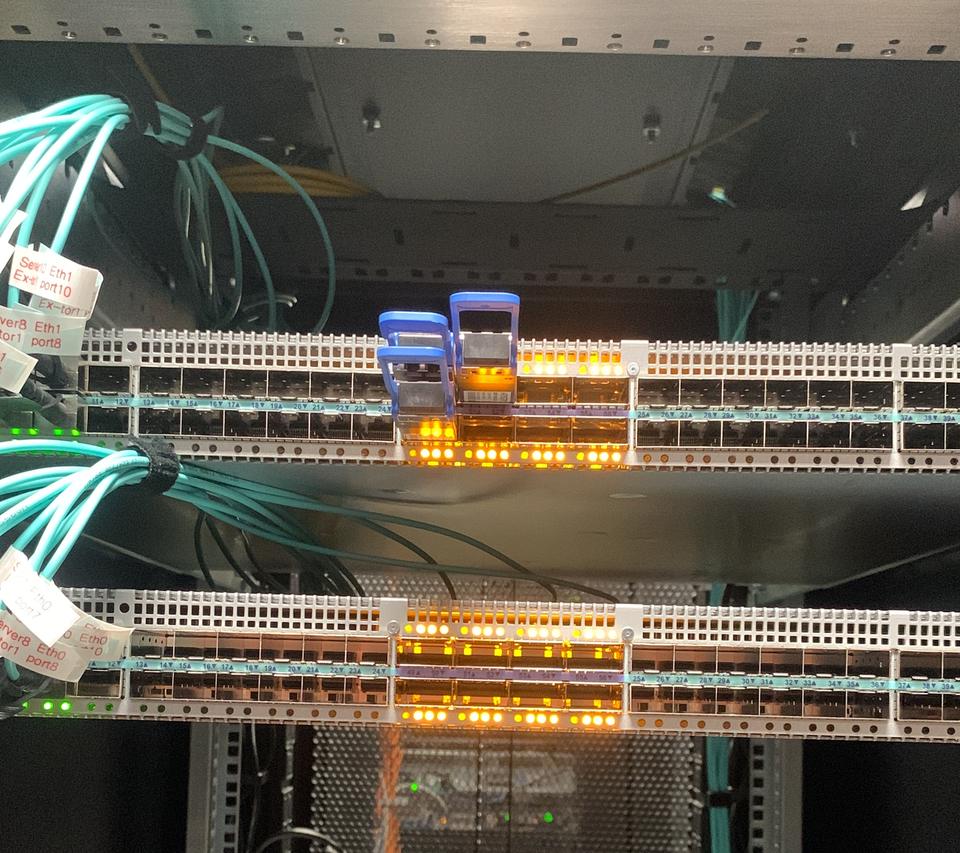 Switches with amber port lights and aqua fibre patching in a rack
