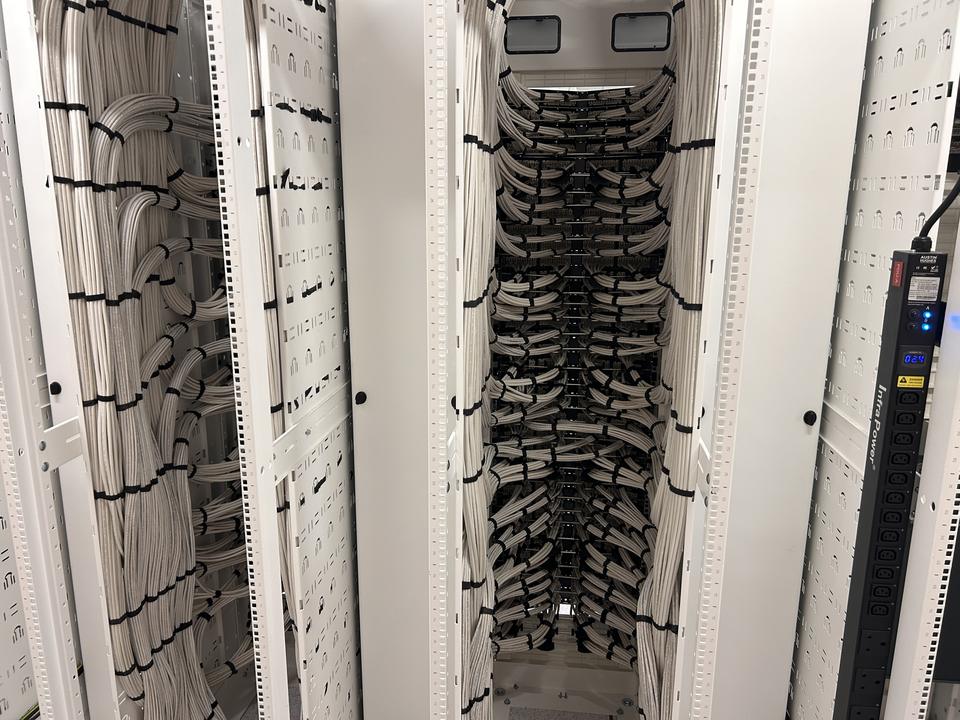 Close-up of vertical cable management in an open rack, with patch leads dressed and bundled by IITECH